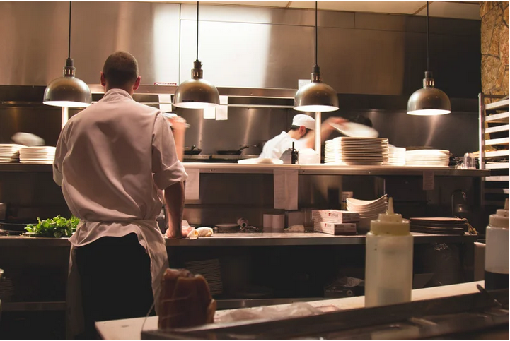 Two men in white chefs' coats in the kitchen of a restaurant