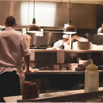 Two men in white chefs' coats in the kitchen of a restaurant