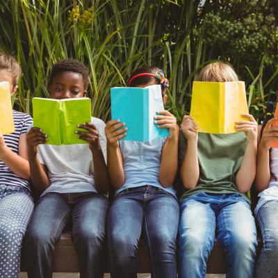 Children reading books that partially obscure their faces. 